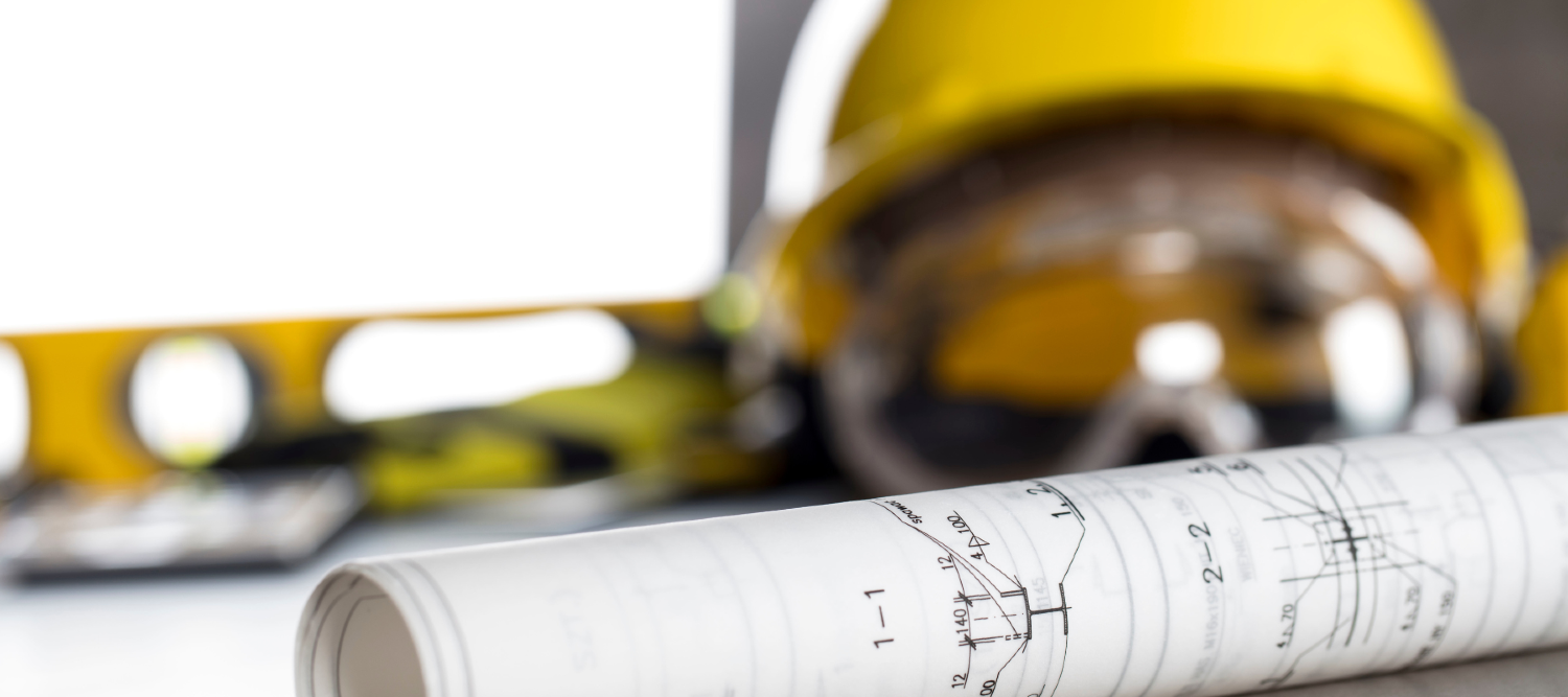 Contractor supplies on a tabletop next to a rolled up blueprint.